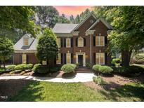 Beautiful brick home with manicured landscaping and a charming front entrance, with a colorful sunset in the background at 5216 Sunset Fairways Dr, Holly Springs, NC 27540