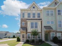 Charming multi-story townhome with stone accents and a well-manicured front lawn at 601 Grand Central Sta, Apex, NC 27502