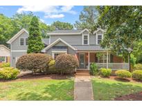 Charming two-story home featuring a brick porch, gray siding and mature landscaping at 6304 Ansley Ln, Raleigh, NC 27612