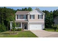 Charming two-story home with a well-manicured lawn and a welcoming front porch and two-car garage at 6729 Osprey Landing Dr, Wendell, NC 27591