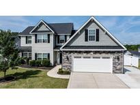 Charming two-story home featuring stone accents, a two-car garage, and well-manicured landscaping at 77 Redpine Ct, Clayton, NC 27520