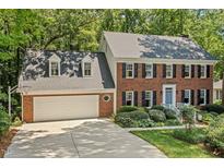 Charming two-story brick home featuring a two-car garage, dormer windows, and professionally landscaped front yard at 8508 Zinfandel Pl, Raleigh, NC 27615