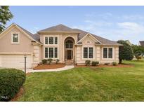 Elegant stucco home featuring manicured lawn, arched entryway, and bright, large windows at 101 Deerwalk Ct, Cary, NC 27513
