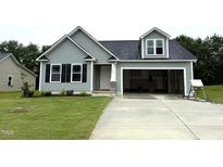Charming single-Gathering home with gray siding, black shutters, an attached garage, and a well-manicured lawn at 104 Oakfield Trace Dr, Four Oaks, NC 27524
