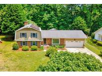 Charming two-story home featuring a well-maintained lawn, mature trees, and attached garage at 1209 Locharron Ln, Cary, NC 27511