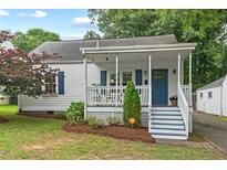 Charming home with a welcoming porch, a blue door, white columns, and updated landscaping at 1826 Northgate St, Durham, NC 27704