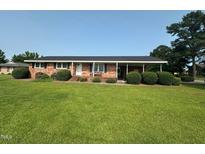 Charming one-story brick home with well-maintained lawn, trimmed shrubs, and a covered carport at 202 Camelia Dr, Princeton, NC 27569