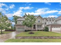 Charming two-story home featuring a stone facade, covered porch, and well-manicured lawn at 216 Pondside Dr, Apex, NC 27539
