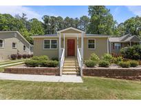 Charming single-story home with a red front door, white railings, brick foundation trim, and a well-manicured lawn at 2710 Broad St, Durham, NC 27704