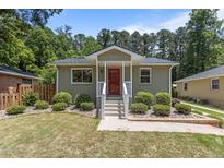 Charming single-story home showcasing a red door and lush landscaping at 2712 Broad St, Durham, NC 27704