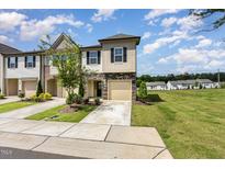 Charming townhome with a stone facade, manicured lawn, and attached one car garage, offering curb appeal at 3015 Cypress Lagoon Ct, Durham, NC 27703