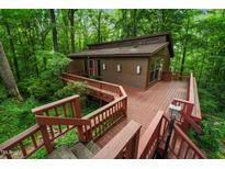 Secluded brown two-story home featuring an expansive wooden deck and lush, mature trees surrounding the property at 3416 Ocotea St, Raleigh, NC 27607
