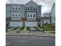 Modern townhome with a two-car garage, stone accents, and manicured lawn at 5330 River Reach Dr, Raleigh, NC 27616