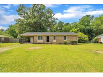Charming single story brick home featuring a well-manicured lawn and mature trees at 605 Sexton Ave, Zebulon, NC 27597