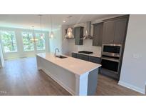 Modern kitchen boasts gray cabinets, stainless appliances, quartz counters, and hardwood flooring at 691 Bandon Aly, Cary, NC 27513