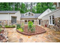 View of a home's charming backyard with stone patio and rock and mulch landscaping at 708 October Woods Rd, Chapel Hill, NC 27516