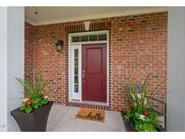 Charming brick home with a red front door and decorative potted plants on a sunny porch at 10310 Sablewood Dr # 111, Raleigh, NC 27617