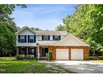 Charming two-story home featuring blue shutters, brick accents, a two-car garage, and a lush front lawn at 104 Benedict Ln, Raleigh, NC 27614