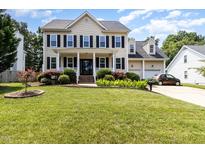 Traditional two-story home with a manicured lawn, black shutters, and an attached two-car garage at 113 Sycamore Ridge Ln, Holly Springs, NC 27540
