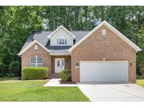 Charming brick home with a two-car garage, manicured lawn and mature trees at 1209 Waterford Green Dr, Apex, NC 27502