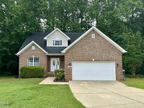 Charming single-Gathering brick home featuring a two-car garage and lush green lawn at 1209 Waterford Green Dr, Apex, NC 27502