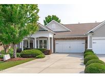 Charming home with a two-car garage, stone accents, well-manicured landscaping, and a welcoming covered front porch at 128 Arvind Oaks Cir, Cary, NC 27519
