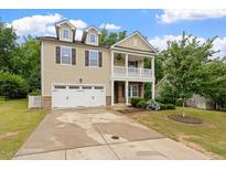 Charming two-story home boasts a well-manicured lawn, attached garage, and inviting covered porch at 143 Thornbury St, Clayton, NC 27527
