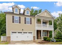 Charming two-story home with a white garage door, beautiful plants, and second story porch at 143 Thornbury St, Clayton, NC 27527