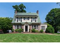 Charming brick home featuring a distinctive green tile roof, manicured lawn, and classic architectural details at 1700 St Marys St, Raleigh, NC 27608