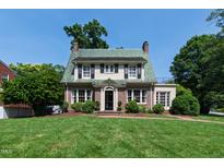 Charming brick and siding home featuring a unique green tiled roof and beautifully maintained front lawn at 1700 St Marys St, Raleigh, NC 27608