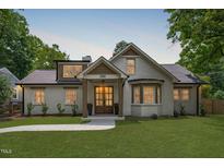 Charming white brick home featuring a manicured lawn, walkway, and a covered front porch with elegant wood accents at 2100 Summit St, Durham, NC 27707
