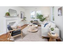 Bright living room with fireplace, stylish furniture, large windows, and beautiful hardwood floors at 2523 Glendale Ave, Durham, NC 27704