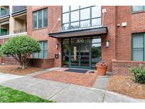 Condominium building entrance with brick facade, glass doors, and well-maintained landscaping and walkway at 300 Finsbury St # 109, Durham, NC 27703