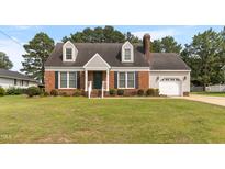 Charming brick home with a manicured front lawn, dormer windows, and attached garage at 304 Westfield Dr, Dunn, NC 28334