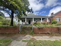 Charming bungalow with a covered front porch, brick foundation, and overgrown front yard at 431 Charles St, Henderson, NC 27536