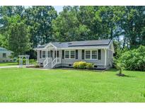 Charming home with gray siding, black shutters, solar panels and well-manicured lawn at 518 Buck Branch Dr, Garner, NC 27529