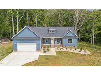 Charming blue home featuring a manicured front yard, garage, and inviting front porch with rocking chairs at 5550 Mountain Trl, Snow Camp, NC 27349