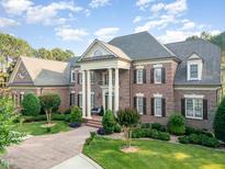Elegant brick home with stately columns, manicured lawn and brick driveway at 5768 Cavanaugh Dr, Raleigh, NC 27614