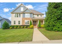 Inviting two-story home with manicured lawn, stone accents, and a charming covered front porch at 900 Green Oaks Pkwy, Holly Springs, NC 27540
