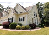 Inviting home with yellow siding, black shutters, manicured landscaping, and charming architectural details at 100 Sheraton Ln, Garner, NC 27529
