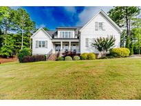 Beautiful white two-story home with a well-manicured lawn and tasteful landscaping and a stairway up to the double front doors at 104 Crosby Ln, Sanford, NC 27330