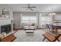 Bright living room featuring a fireplace, ceiling fan, and large windows dressed with white curtains at 107 Covington Dr, Chapel Hill, NC 27514