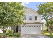 Charming two-story home with neutral siding and a two car garage, framed by mature trees in the front yard at 110 Bray Dr, Mebane, NC 27302