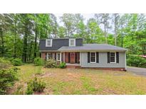Charming two-story home featuring a brick facade and light blue siding, surrounded by lush green trees at 1116 Little Creek Rd, Durham, NC 27713