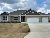 New single-story home featuring a 3-car garage, neutral siding, and an open front yard with fresh sod at 120 Newport Lndg # 99, Garner, NC 27529