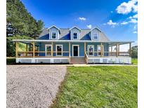 Charming blue home with a wide, inviting wrap-around porch and well-maintained lawn at 1283 Ennis Rd, Angier, NC 27501