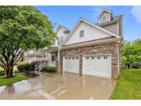 Beautiful home with stone accents, a two-car garage, covered porch, and a manicured lawn under a bright blue sky at 2067 Glenkirk Dr, Burlington, NC 27215