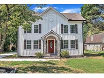 Charming two-story home featuring board and batten siding, a stone front porch, and a red front door at 305 W Canary St, Dunn, NC 28334
