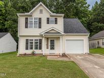 Charming two-story home with a well-manicured lawn, attached garage and 'welcome' sign hanging near the front door at 4020 Mindspring Dr, Raleigh, NC 27610