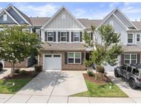 Charming townhouse with stone accents, a two-car garage, and a well-manicured front yard at 409 Rhamkatte Rd, Holly Springs, NC 27540